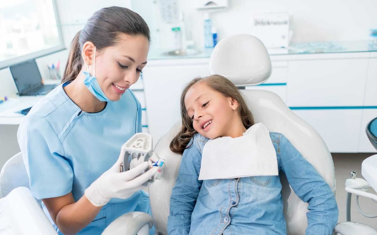 Dentist showing a young patient how to care for their teeth
