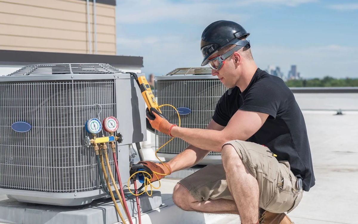 HVAC technician servicing a rooftop air conditioning unit with gauges